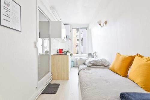 - un salon blanc avec un canapé et des oreillers jaunes dans l'établissement Studio Quartier Tour Eiffel 9 Free Netflix, à Paris