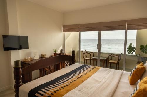 a bedroom with a bed and a view of the ocean at Neevana Hotel Hikkaduwa in Hikkaduwa