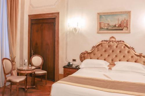 a bedroom with a large bed and a table and chairs at Hotel Ai Cavalieri di Venezia in Venice