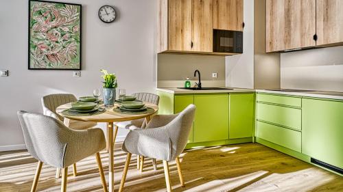 a kitchen with green cabinets and a table with chairs at Źródło Izery przy gondoli VIP Sauna, Siłownia, Bawialnia by Royal Aparts in Świeradów-Zdrój