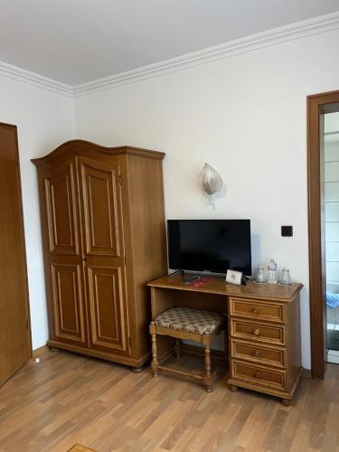 a room with a desk with a television and a cabinet at Hotellerie Gasthaus Schubert in Garbsen