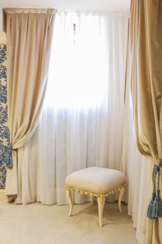 a chair sitting in front of a window with curtains at Hotel Ai Cavalieri di Venezia in Venice