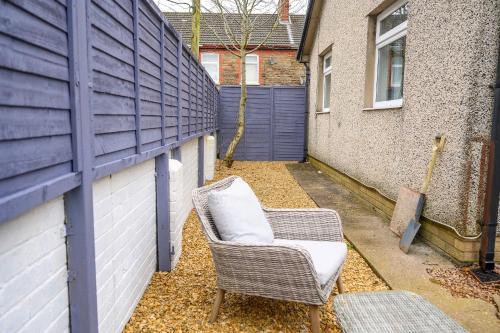 a wicker chair sitting in front of a fence at Vinmar Very Special Bungalow In Charming Area Of Wales By StayStaycations in Pengam