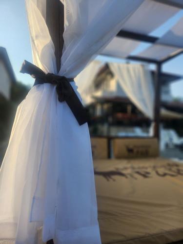 a wedding dress with a black bow on a bed at Бадевски рай-къща Любов in Badewzi