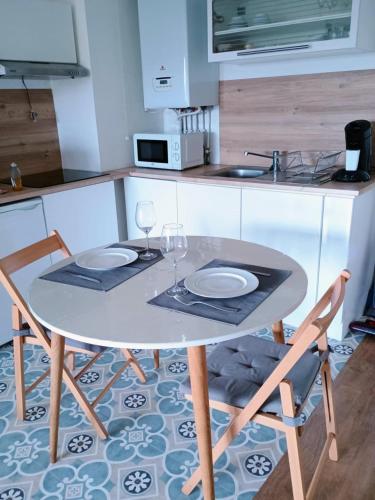 - une table avec deux verres et deux chaises dans la cuisine dans l'établissement Appartement T2, à Le Bouscat