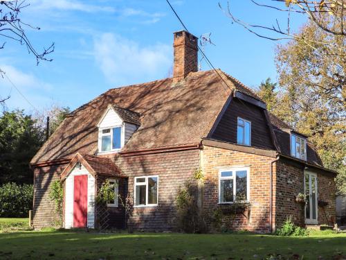 an old brick house with a red door at Golford Cottage in Cranbrook