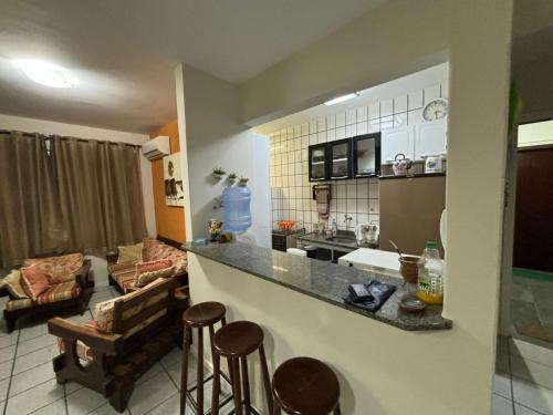 a kitchen and living room with a counter and stools at Apartamento na praia de Bombas Edifício Umuarama nº 63, bloco B in Bombinhas