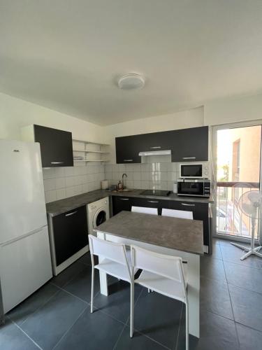 une cuisine avec une table et un réfrigérateur blanc dans l'établissement Appartement Caroline Proche mer & ville CALVI, à Calvi