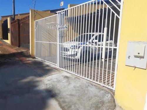 a white fence with a car parked behind it at Família Durães Kitnets01 in Londrina