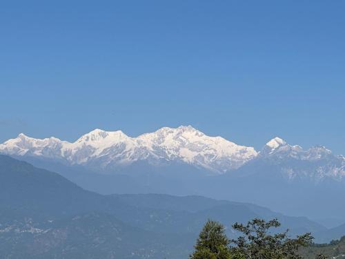 a blue lake with snow capped mountains in the background at Hotel Basera in Darjeeling
