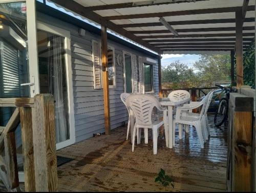 une terrasse couverte avec une table et des chaises sur une maison dans l'établissement Camping Del Mar 137, Mobile Home O'Hara OTiny930, 3 chambres, 2 salles de bain, 6 personnes, bord de mer, à Argelès-sur-Mer