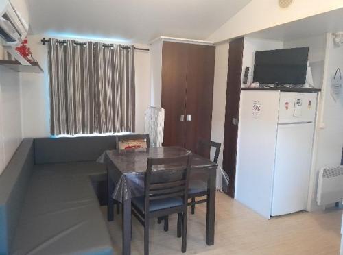une salle à manger avec une table et un réfrigérateur dans l'établissement Camping Del Mar 137, Mobile Home O'Hara OTiny930, 3 chambres, 2 salles de bain, 6 personnes, bord de mer, à Argelès-sur-Mer