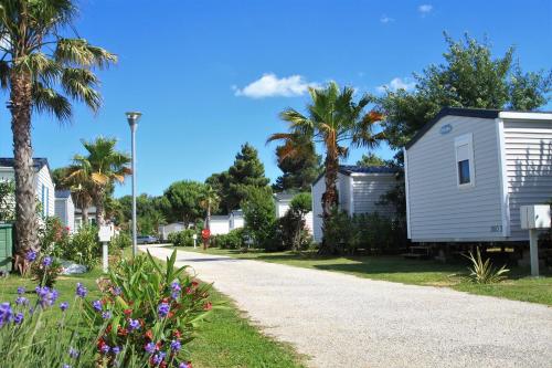 une maison et une route avec des palmiers et des fleurs dans l'établissement Camping Del Mar 137, Mobile Home O'Hara OTiny930, 3 chambres, 2 salles de bain, 6 personnes, bord de mer, à Argelès-sur-Mer