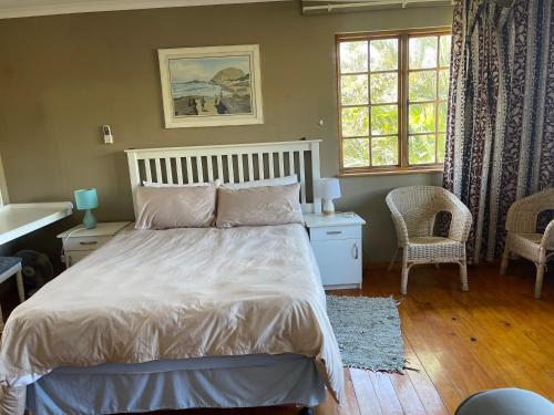 a bedroom with a white bed and a window at Wooden house lodge in KuGqangushe
