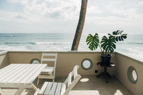 a table and chairs on a balcony overlooking the ocean at Neevana Hotel Hikkaduwa in Hikkaduwa