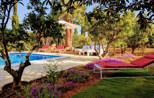 a garden with a swimming pool and a red chaise lounge at Villa Pranayama in Santa Gertrudis de Fruitera