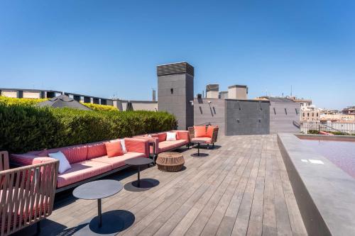 a rooftop patio with couches and tables on a building at Midtown Apartments in Barcelona