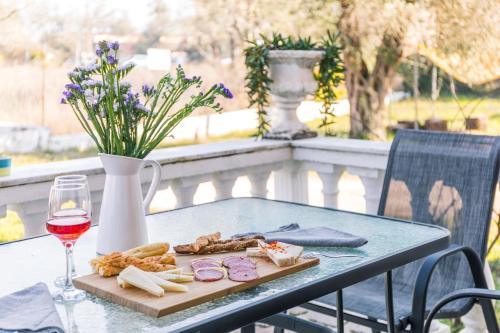 a table with a plate of food and a glass of wine at Lamda Apartments By Estia in Roda