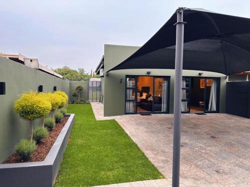 a large black umbrella in front of a house at Boutique On Madeliefie in Welkom