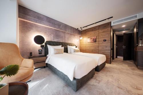 a bedroom with a large white bed and a chair at Hotel Simona Halep - Poiana Brasov in Poiana Brasov