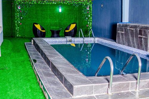 una piscina con césped verde y sillas en una habitación en 2 Bedroom Luxury Apartment with Pool -24Hrs Power -PS4, en Lagos