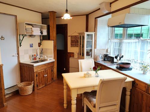 a kitchen with a table and a table and chairs at Folks House Room B in Eniwa