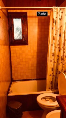 a bathroom with a tub and a toilet and a shower curtain at Cabañas Lothlorien in Villa Yacanto