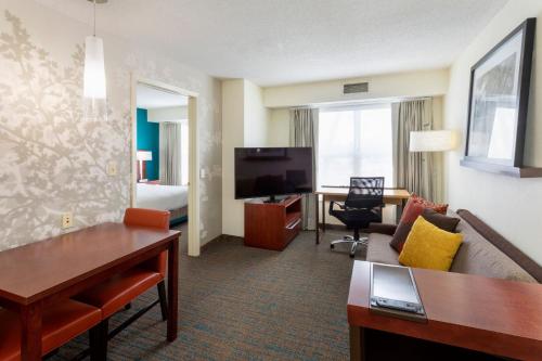a hotel room with a couch and a table and a television at Residence Inn Minneapolis St. Paul/Roseville in Roseville