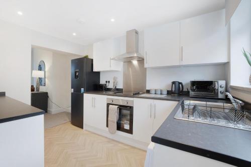 a kitchen with white cabinets and a black refrigerator at NEW! Spacious 4BR in Sidney in Bishop Auckland