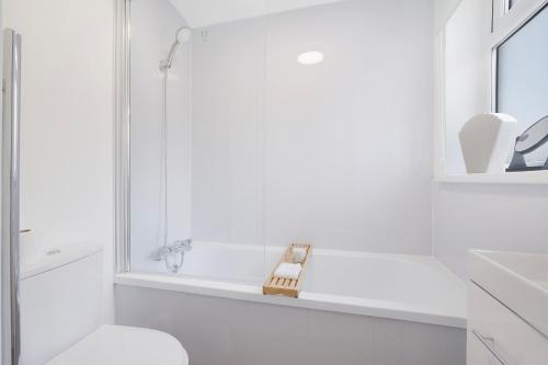 a white bathroom with a tub and a toilet at NEW! Spacious 4BR in Sidney in Bishop Auckland