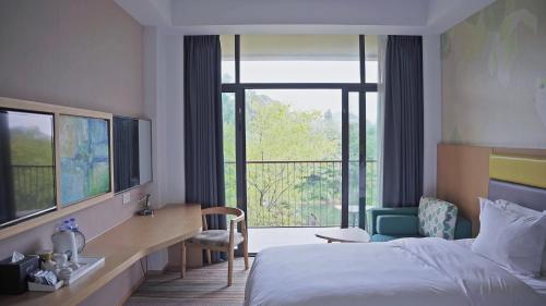a hotel room with a bed and a large window at Holiday Inn Express Emei Mountain by IHG in Emeishan