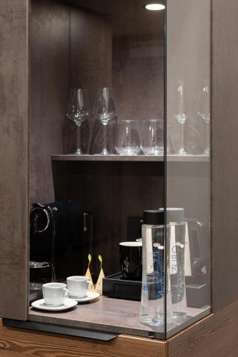 a glass cabinet with cups and glasses on a counter at Hotel Simona Halep - Poiana Brasov in Poiana Brasov