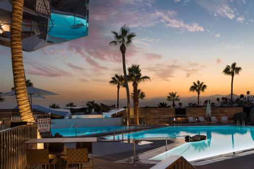 a pool at a resort with palm trees at La Isla y el Mar, Hotel Boutique in Puerto del Carmen