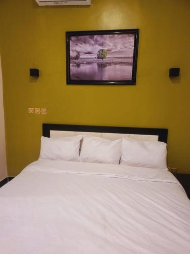 a bedroom with a white bed with a picture on the wall at House 55b in Rubuchi
