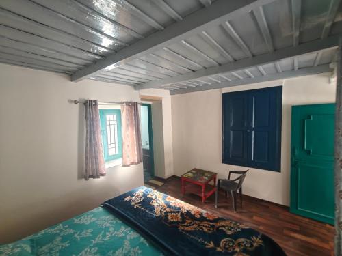 a bedroom with a bed and a chair and windows at The Eleventh homestay in Kasol