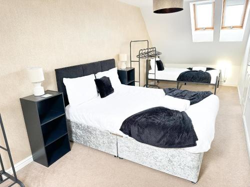 a bedroom with two beds with white sheets and black blankets at Modern 4 Beds House With FREE Parking in Kenton