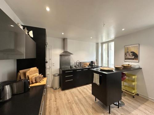 a kitchen with a black island in a room at Maison familiale-jardin-50m du Loing-tout à pieds in Moret-sur-Loing