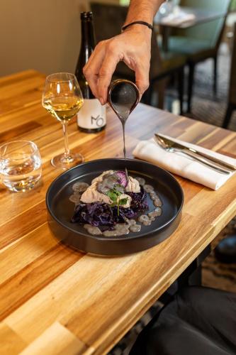 a person holding a spoon over a plate of food at Novotel Lyon Gerland Musée des Confluences in Lyon