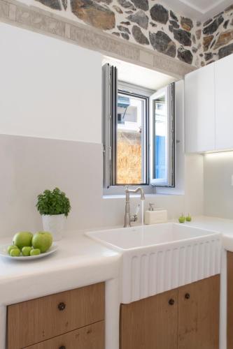 a white kitchen with a sink and a window at Aurora House Astypalea A in Pera Gyalos