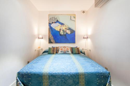 a bedroom with a blue bed with a painting on the wall at Loft Valencia centro - Vive el corazón de la ciudad in Valencia