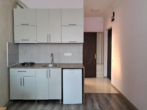 a kitchen with white cabinets and a sink at Karvi Hostel & Suites in Batumi
