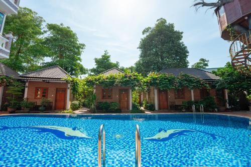 a swimming pool in front of a house with dolphins in the water at Duy Ngoc Resort Phu Quoc in Phu Quoc