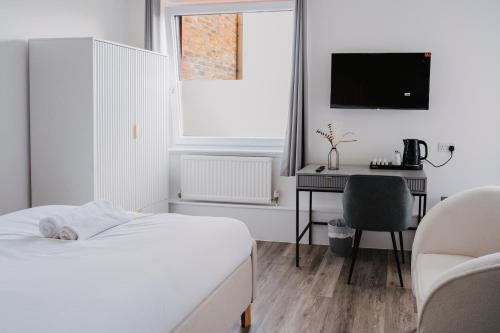 a bedroom with a bed and a desk and a television at WNS Skylines Village in London