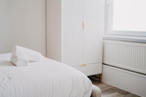 a white bedroom with a bed and a window at WNS Skylines Village in London