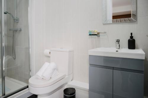a white bathroom with a toilet and a sink at WNS Skylines Village in London