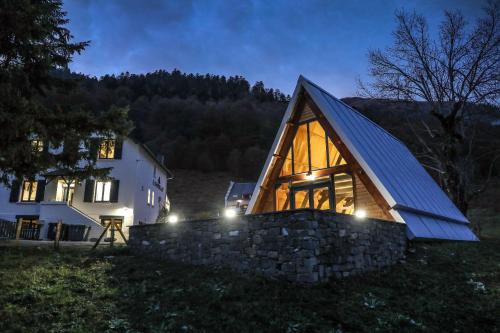 a wooden house with a stone wall at night at Hotel O Chiroulet in Bagnères-de-Bigorre
