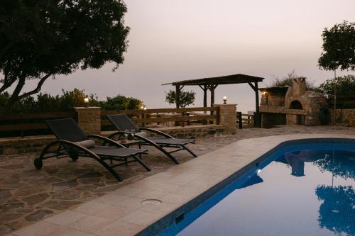 a pool with two chairs and a gazebo at Greco Levantes Villas in Triopetra