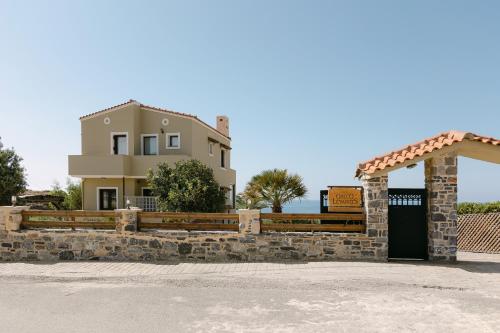 a house behind a stone fence with a gate at Greco Levantes Villas in Triopetra