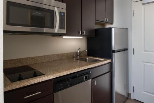 a kitchen with a sink and a microwave and a refrigerator at TownePlace Suites Richland Columbia Point in Richland