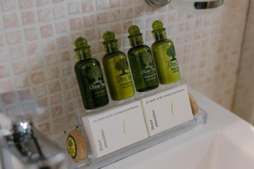 three bottles of olive oil on a shelf in a bathroom at Greco Levantes Villas in Triopetra